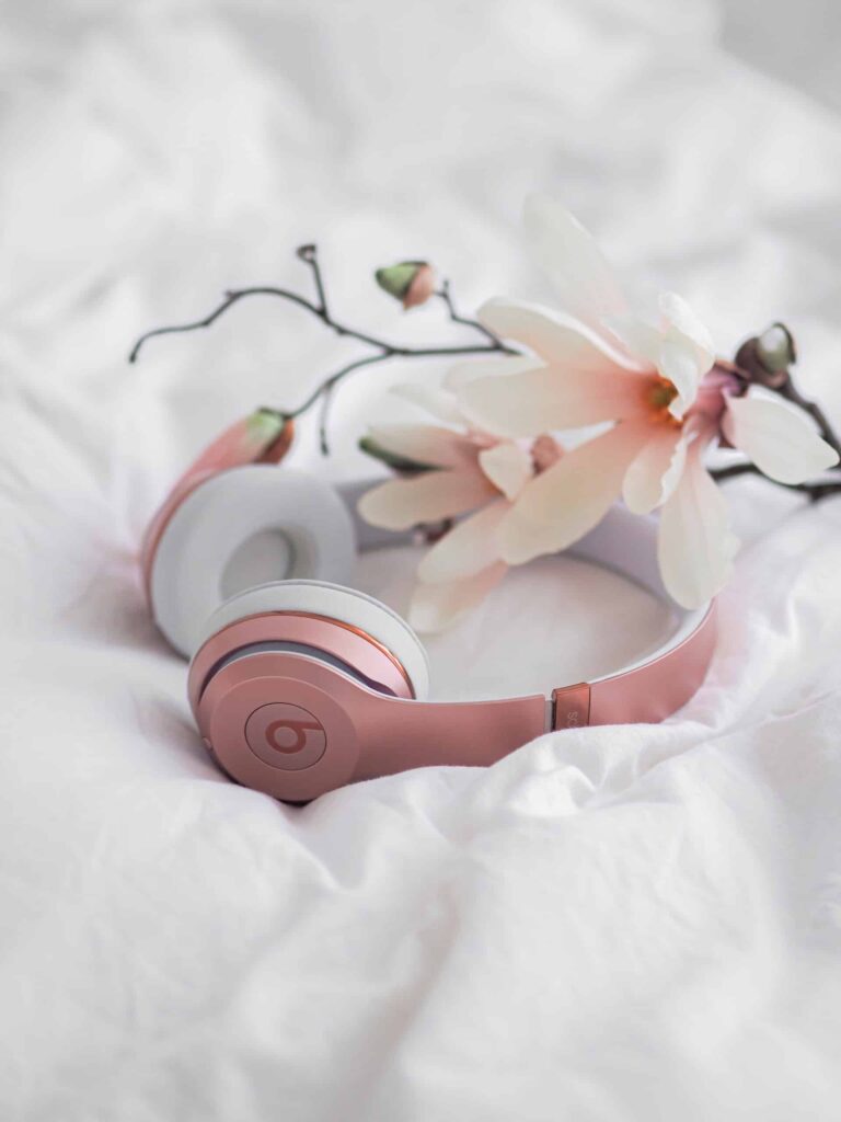 Pink headphones and a flower on a bed