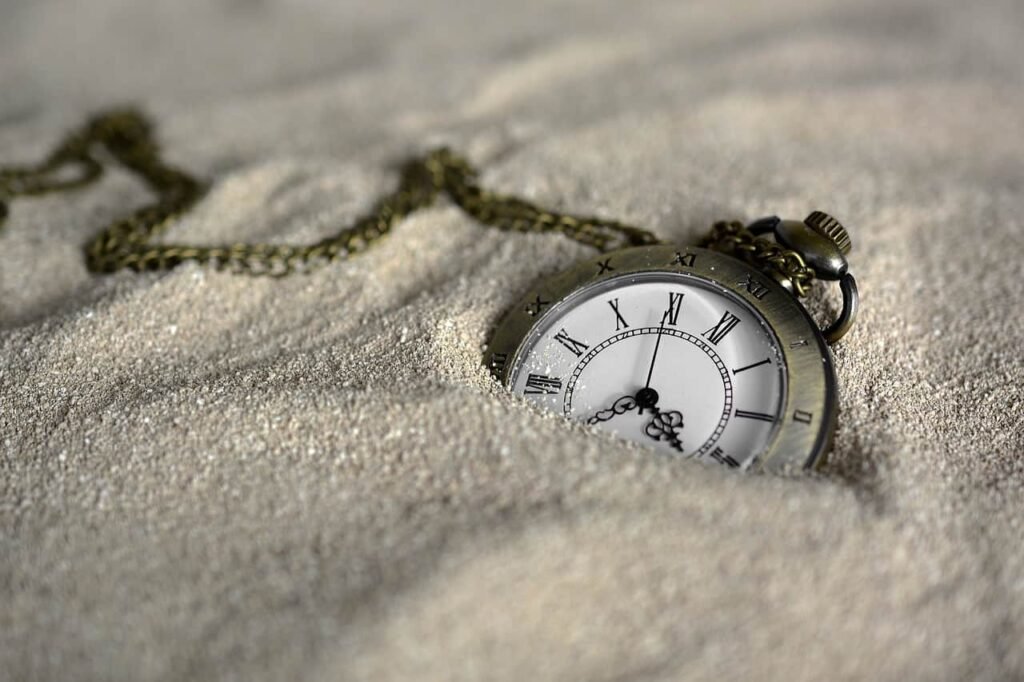 A pocked watch buried in sand