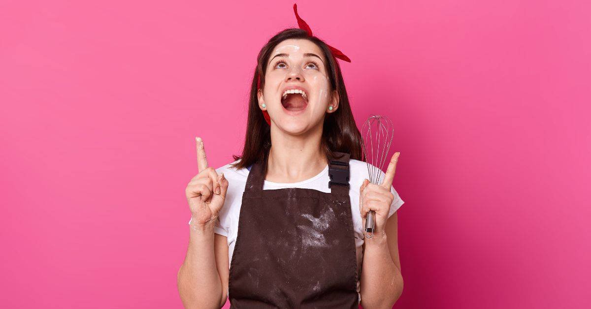 An energetic woman wearing an apron on pink background